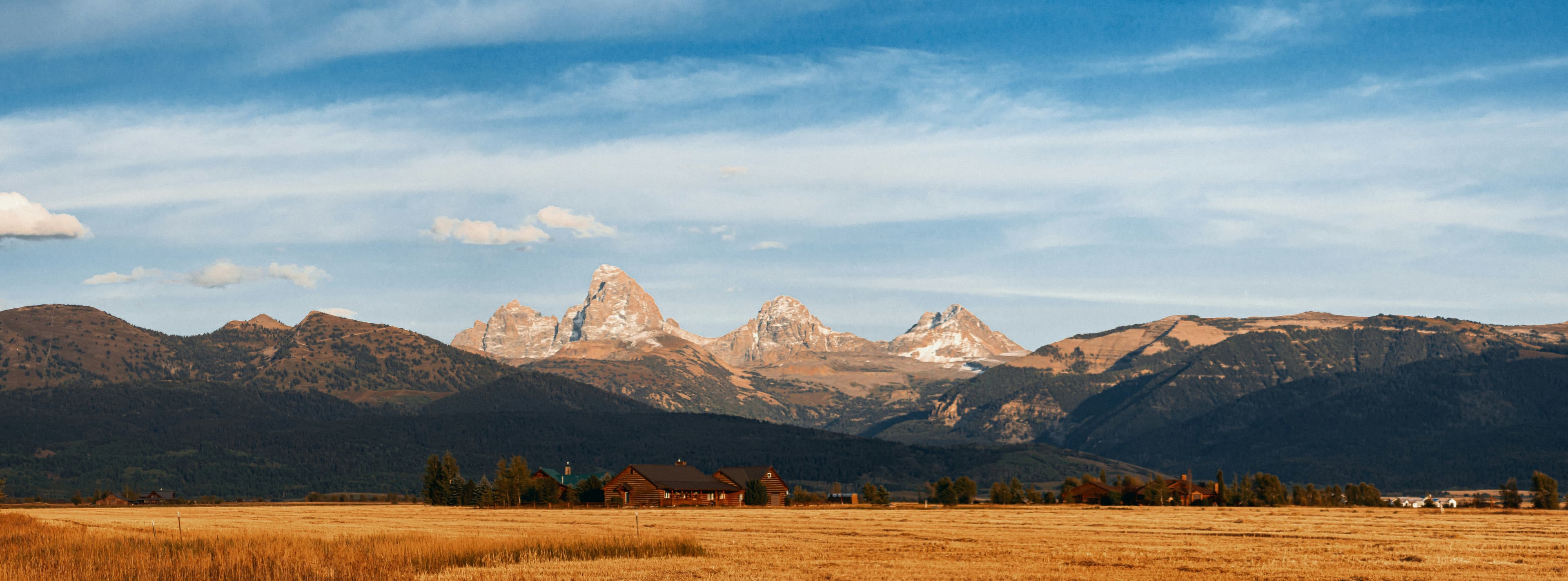 Grand Teton mountain range above open fields and homes